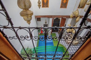 An indoor courtyard with a pool, a wooden staircase, and hanging lamps. - Riad Old city palace (Fes)