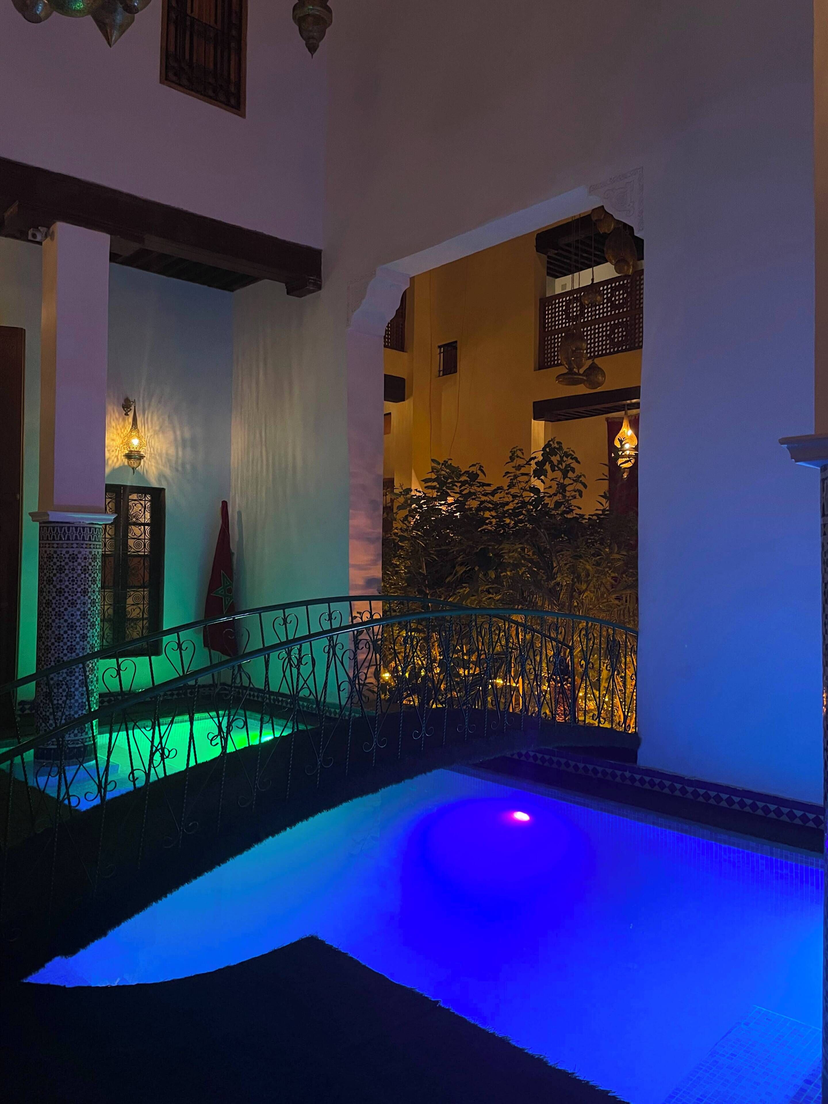 A pool area with a metal railing, a water feature, and a view of a building with balconies.
