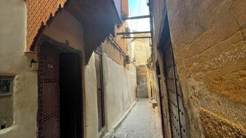 Een smalle steeg met een gebouw aan de linkerkant, voorzien van een bordje met de tekst 'Riad Old City Palace'.
