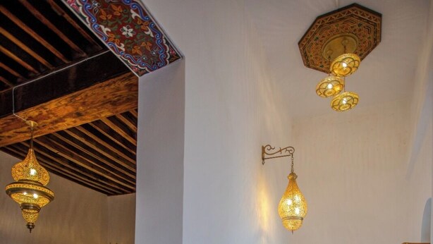 Una habitación con una cama, un armario de madera y lámparas colgantes.