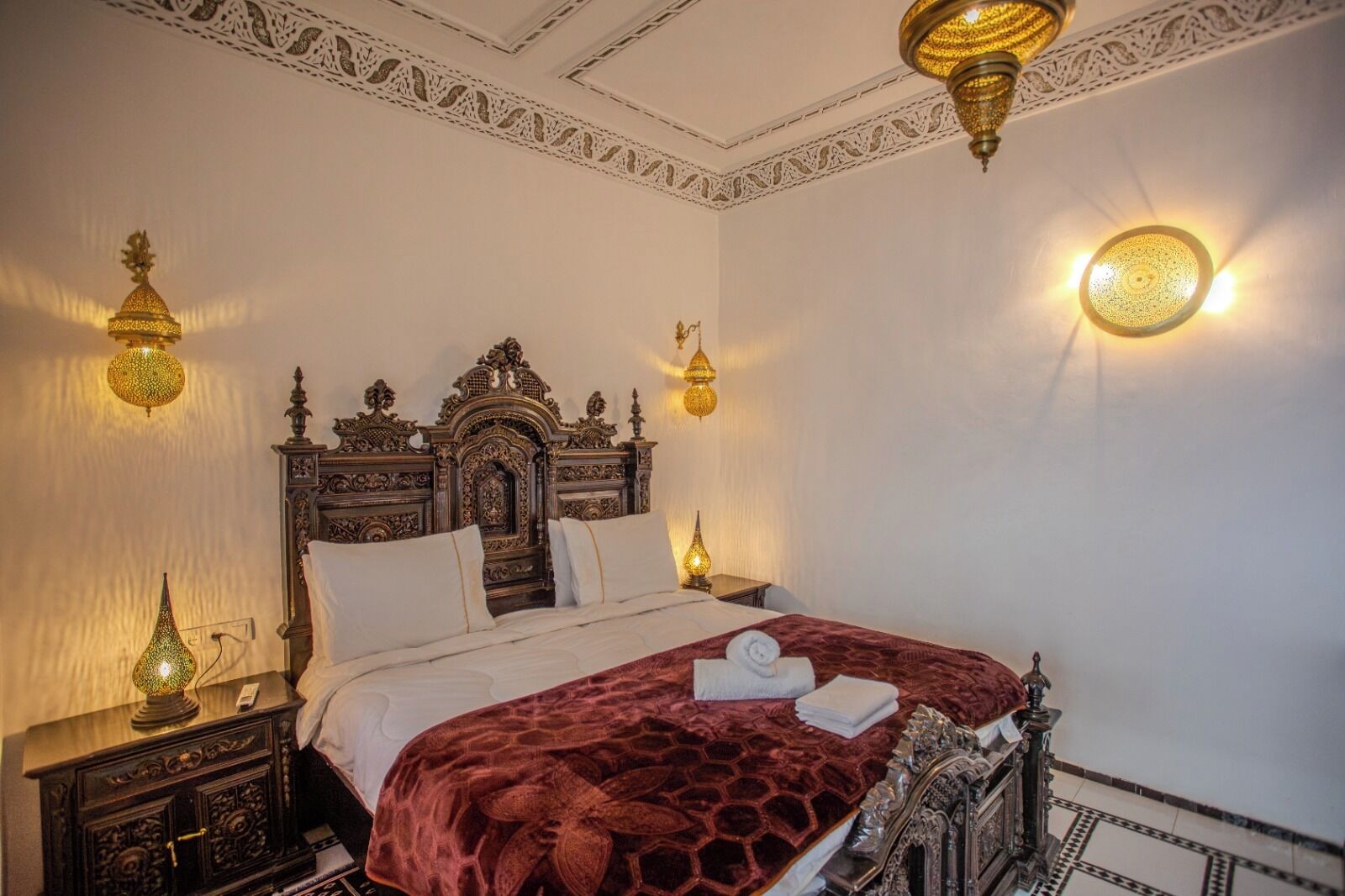A room with an ornate bed, two bedside lamps, and a decorative ceiling.