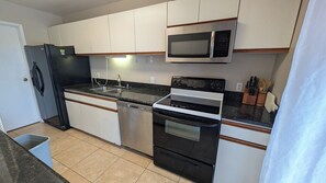 A kitchen with a refrigerator, dishwasher, microwave, oven, and granite countertop. - Vis Ton Reve- 2-bedroom condo in amazing Christiansted with AC and comfort (Christiansted)