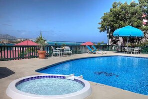 Uma piscina com hidromassagem, espreguiçadeiras e guarda-sóis.