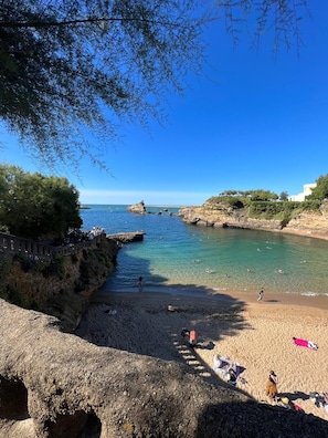 Una playa costera con agua cristalina, terreno rocoso y un muro de piedra.