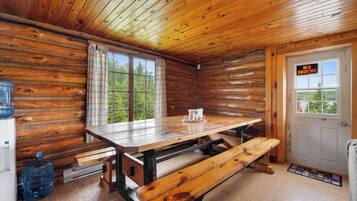 L’intérieur d’une cabine est aménagé avec une table en bois, des bancs, un réfrigérateur et une porte sur laquelle est apposé un panneau indiquant « Il est interdit de fumer ».