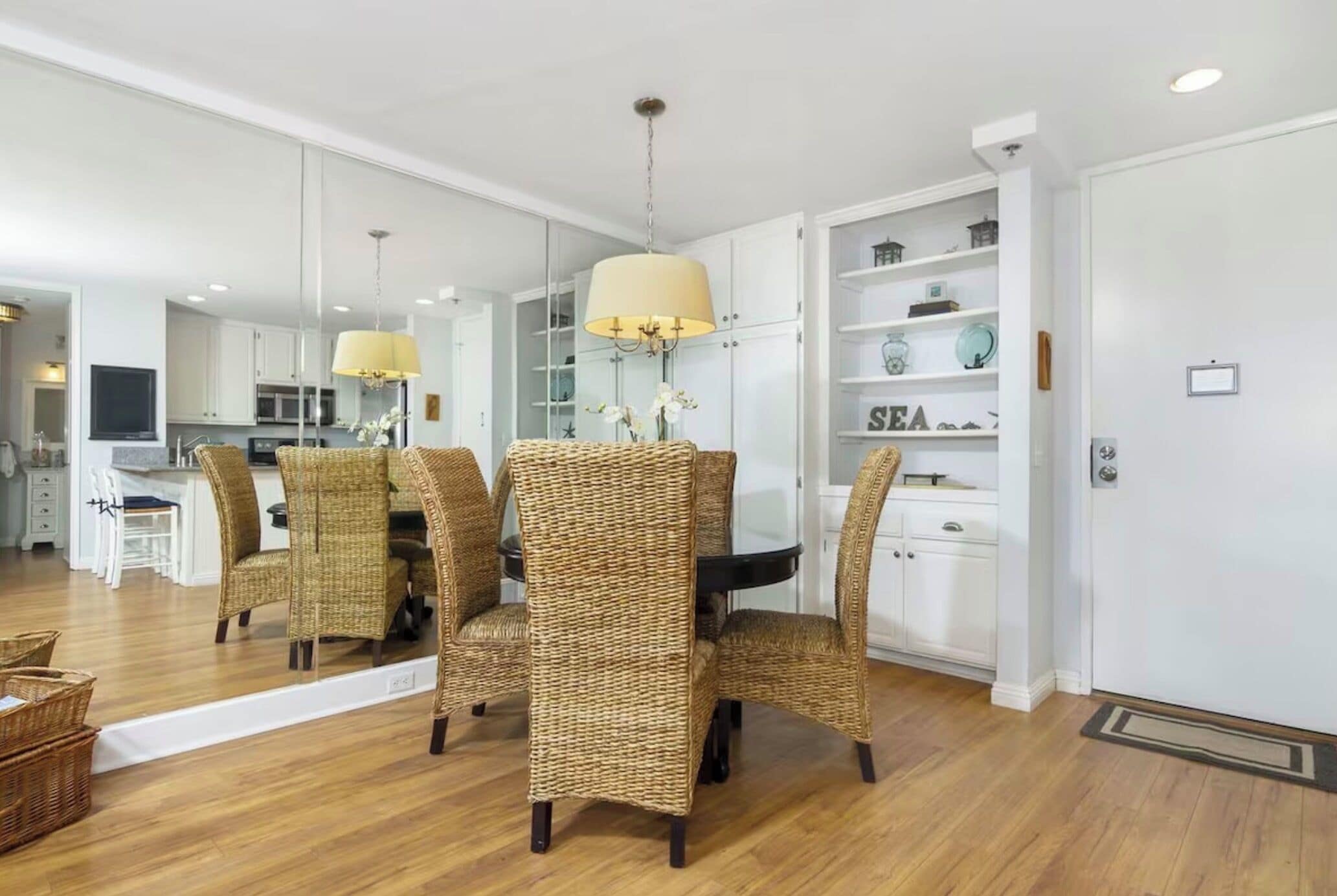A dining area with wicker chairs, a central table, and a chandelier.