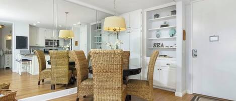 A dining area with wicker chairs, a central table, and a chandelier.