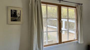 A room with a large window, a curtain rod, and a framed picture on the wall.
