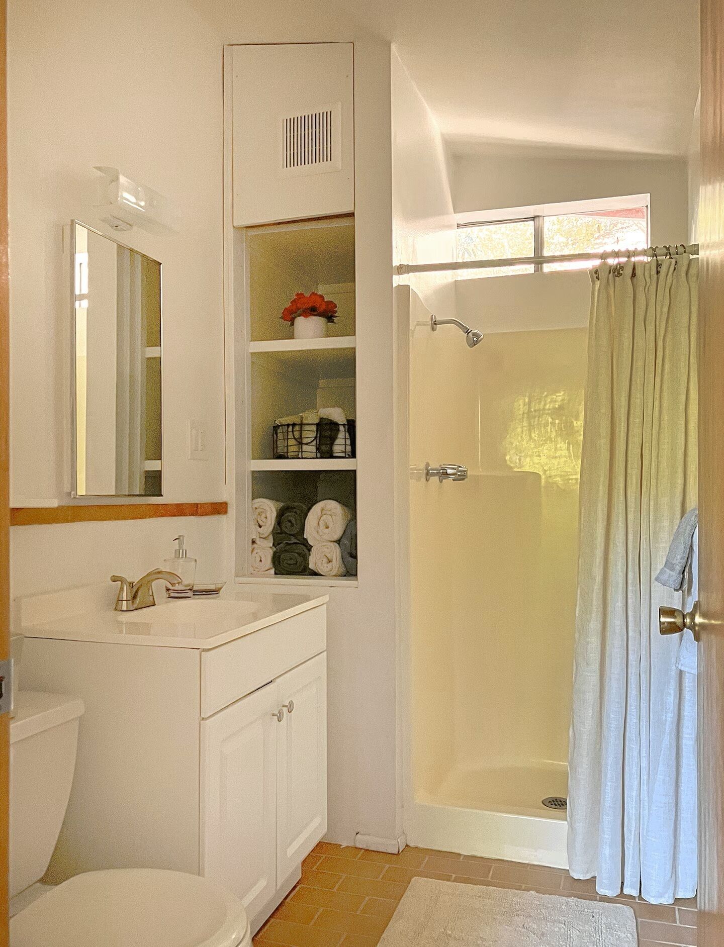 A bathroom with a toilet, sink, mirror, shower, and a towel rack.