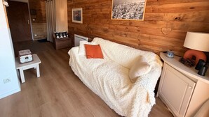 Et hyggeligt rum med en trævæg, en hvid sofa, et lille bord og et skab.