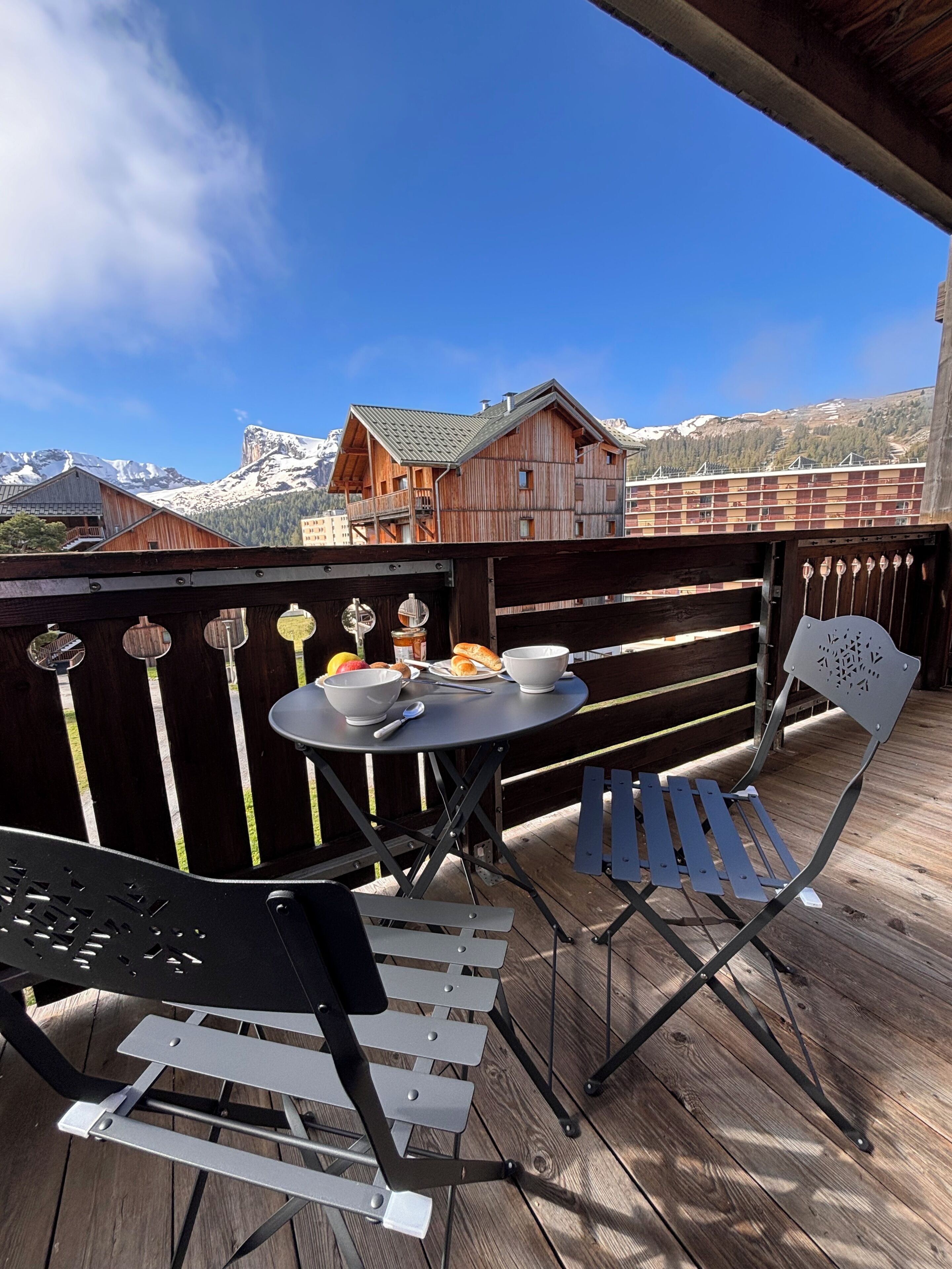 A wooden deck with a table and chairs, overlooking a mountain landscape.