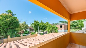 A balcony with a tiled roof, a view of a residential area, and a clear sky. - Mansão-7quartos em Porto de Galinhas-165 (Camela)