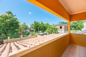 A balcony with a tiled roof, a view of a residential area, and a clear sky. - Mansão-7quartos em Porto de Galinhas-165 (Camela)