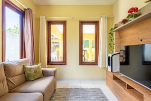 A living room with a sofa, a flat-screen TV, and two windows with curtains. - Mansão-7quartos em Porto de Galinhas-165 (Camela)