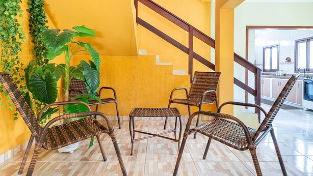 A room with a staircase, wicker furniture, and a view of a kitchen. - Mansão-7quartos em Porto de Galinhas-165 (Camela)