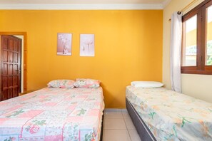 Ein Schlafzimmer mit zwei Betten, einer Holztür und einem Fenster mit Vorhängen.