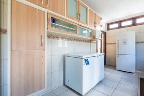 Eine Küche mit Holzschränken, einem weißen Kühlschrank und einer Mikrowelle.