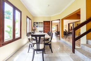 A dining area with a large table and chairs, a wooden staircase, and a view of the outdoors. - Mansão-7quartos em Porto de Galinhas-165 (Camela)