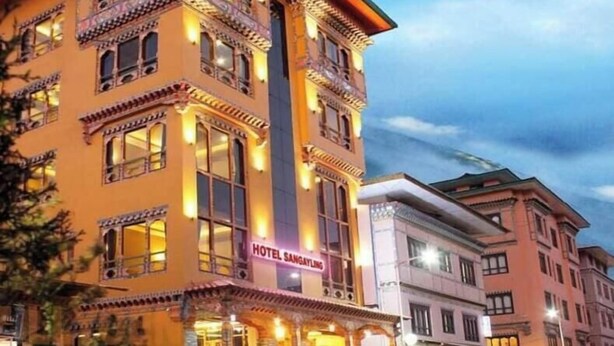 A multi-story hotel with a traditional architectural style, featuring ornate balconies and a prominent entrance. - Hotel Sangayling  (Paro)