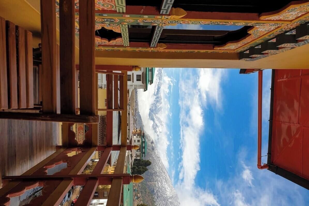 A traditional building with a staircase leading to a balcony overlooking a mountainous landscape.