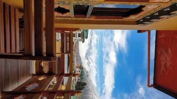 A traditional building with a staircase leading to a balcony overlooking a mountainous landscape.