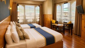 A hotel room with two beds, a desk, and a chair. - Hotel Sangayling  (Paro)