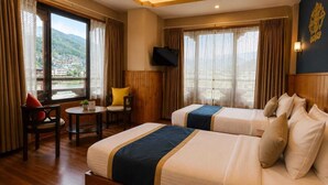 A hotel room with two beds, a TV, a small table, and a chair. - Hotel Sangayling  (Paro)