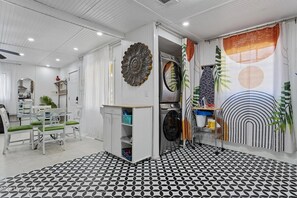 A modern interior with a dining area, a washing machine, and a patterned floor. - Yellow Cottage, Sleeps 4, Game Room, Fire Pit (Gulfport)
