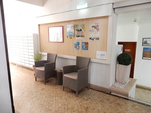 A reception area with wicker chairs, a bulletin board with various notices, a sign pointing to the bar, and a small decorative plant. - Superior 2-Bedroom Apartment – Garden View with Shared Pool (Portimão)