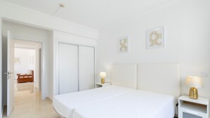 Quarto de hotel com uma cama grande, mesas de cabeceira, um guarda-roupa e uma porta que dá para outro espaço.