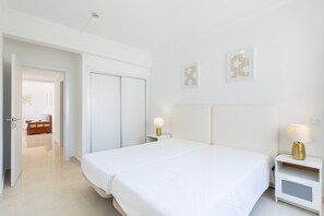 Ein Hotelzimmer mit einem großen Bett, Nachttischen, einem Kleiderschrank und einer Tür zu einem weiteren Raum.