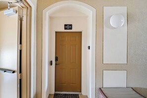 Entrada de hotel com porta marrom, fechadura eletrônica e uma placa sobre a porta.
