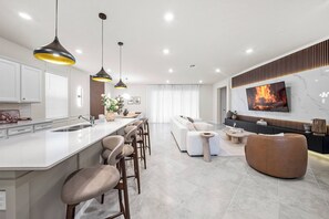 A modern kitchen with a central island, bar stools, and pendant lighting. - 8BR house with private pool and game room (Clermont)