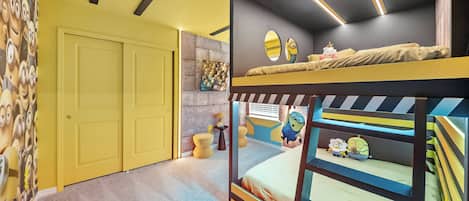 Habitación con literas, una puerta, una pared con un mural con tema de Minions y una mesita con una lámpara.
