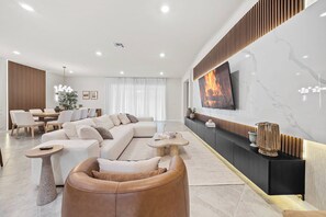 A modern living room with a sectional sofa, a leather armchair, a coffee table, and a TV mounted on a marble wall. - 8BR house with private pool and game room (Clermont)