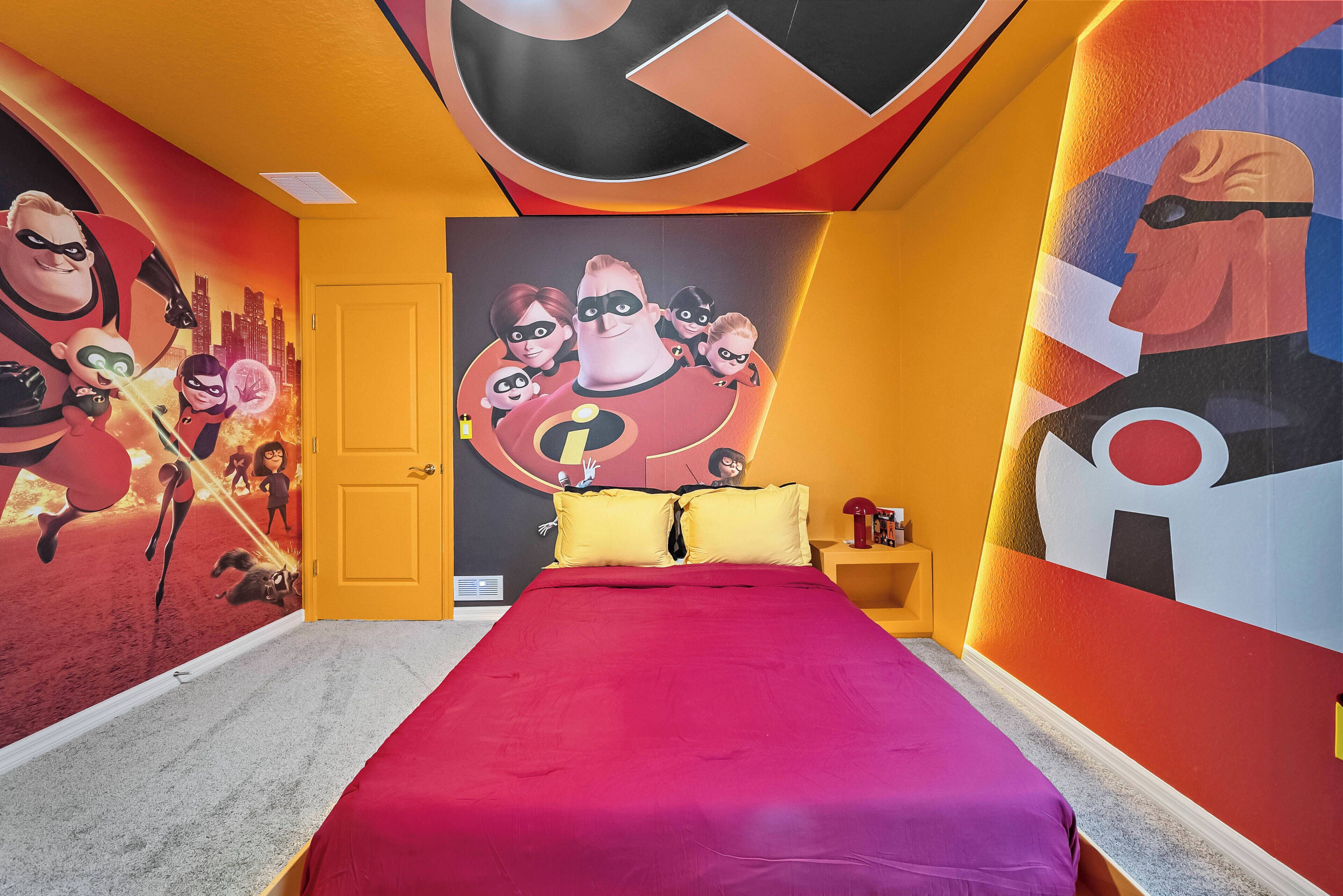 Une chambre avec une grande fresque représentant des personnages de dessins animés, une couvre-lit rouge et une porte jaune.