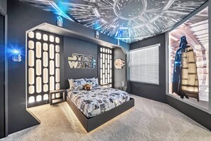 Une chambre décorée sur le thème de Star Wars, avec un lit, des œuvres d’art murales de Star Wars et un motif au plafond.