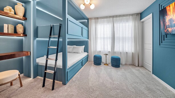 Um quarto com uma cama beliche, uma escada, uma mesa pequena e um quadro na parede.