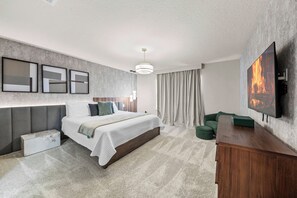 Ein modernes Schlafzimmer mit einem großen Bett, einem an der Wand montierten Fernseher und einem Nachttisch aus Holz.