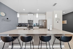 A modern kitchen with a central island, bar stools, and a clock on the wall. - 4BR house sleeps 10 with private pool in kissimmee (Kissimmee)
