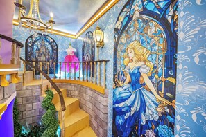 Eine prachtvolle Treppe mit einer Wandmalerei einer Prinzessin, aufwendigen Geländern und einem Chandelier.