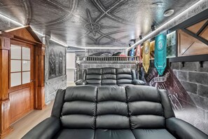 Ein Zimmer mit Kamin, einer großen Ledersofa und einer Wand mit Wandgemälde.
