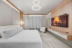 Ein modernes Hotelzimmer mit einem großen Bett, einem flachbildfernseher an der Wand und einer kleinen Sitzecke.