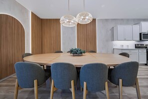 A modern dining area with a round table, six chairs, and a potted plant. - 10BR house with private pool and game room (Clermont)