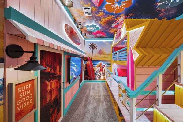 Um corredor colorido com placa de surf shop, placa de salva-vidas e um mural com cena de praia.