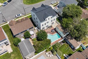 A residential property with a swimming pool, a covered patio, and a large house with a sloped roof. - Haven on Heald | 7BR + Pool Near Beach (Brigantine)