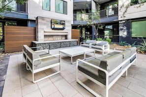 Een terras met moderne meubels, een stenen openhaard en een flatscreen televisie aan de muur.