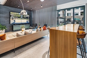 A modern interior with a long wooden bench, a dining area, and a large window offering a view of the outside. - Escape To The Sage Room 2 BR Suite Tempe Town Lake (Tempe)