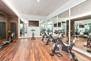 Een sportschool met trainingsapparatuur, houten vloeren en spiegels.