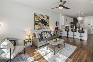 Un salon moderne avec un canapé, une table basse et un coin repas équipé de tabourets de bar.